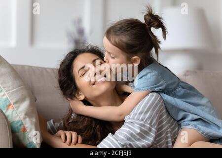 Little daughter gently cuddles kisses mother on cheek showing love Stock Photo
