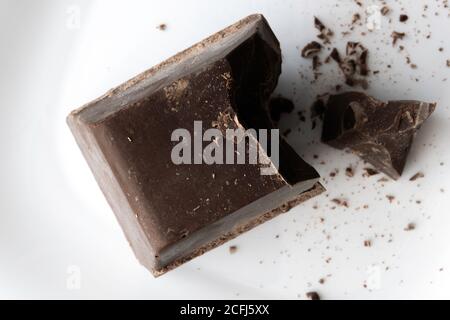 a large chopped piece of chocolate lies on a white ceramic plate Stock Photo