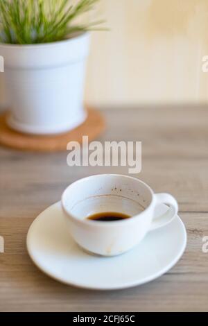 Dirty coffee cup and saucer on a wooden countertop in the kitchen. Morning breakfast concept. Vertical photo Stock Photo