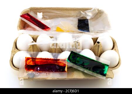 preparation for Easter, white chicken eggs in a box and bags of colorful paints for eggs on the white background Stock Photo