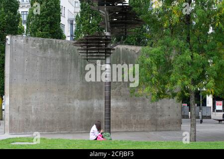 Manchester Piccadilly bus station. Minimalist Japanese architect Tadao Ando designed curved concrete wall in Picadilly Gardens with woman sat at base. Stock Photo