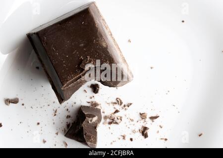 a large chopped piece of chocolate lies on a white ceramic plate Stock Photo
