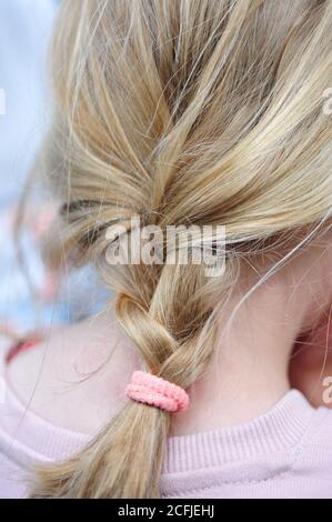 Vertical shot of a simple braided blonde hair under the lights with a blurry background Stock Photo