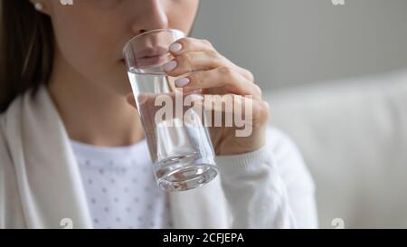 Close up young healthy woman drinking glass of pure water. Stock Photo