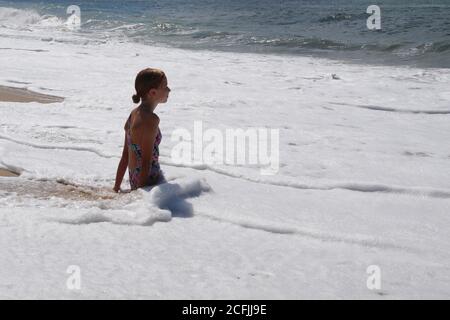 portrait of teenage girl in bikini sitting in the water Stock