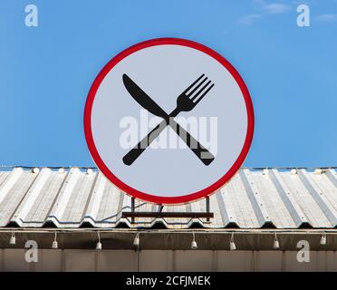 A Circle billboard is installed on a roof and show icon crossing forks with a knife. Stock Photo