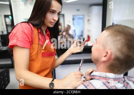 Hairdresser holds hair clipper in his hands and communicates with the client. Stock Photo