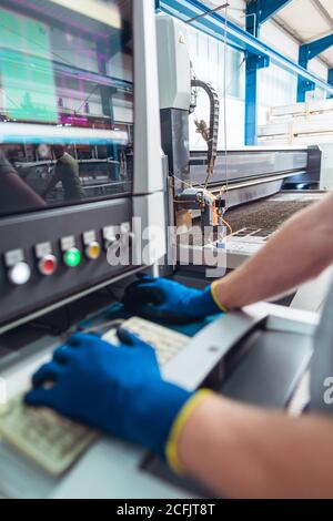 Worker operating a water jet cutting machine by pressing buttons Stock Photo