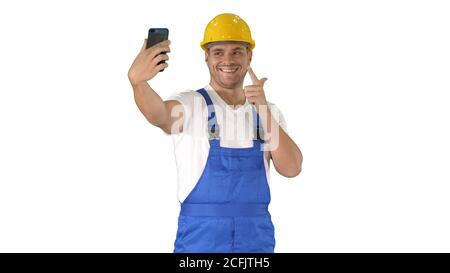 Smiling handsome young builder making selfie with mobile phone on white background. Stock Photo