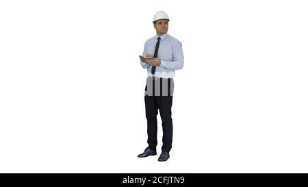 Man in helmet and formal clothes walking looking around and making notes on white background. Stock Photo