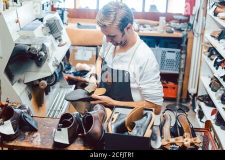 Shoemaker with shoes to repair on a rack in his workshop Stock Photo