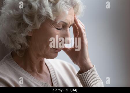 Close up unhappy frustrated mature woman touching forehead, feeling pain Stock Photo