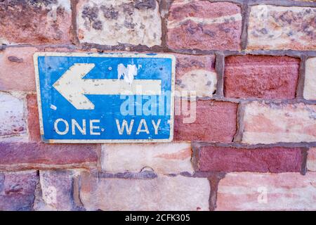 Brick Wall with Blue and White One Way Sign Stock Photo