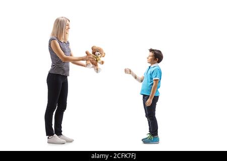 Full length profile shot of a woman giving a teddy bear to a boy isolated on white background Stock Photo