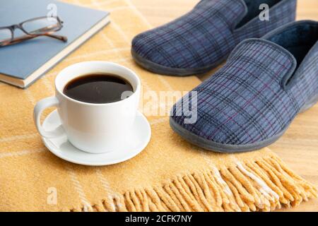 Male home slippers, coffee, book and wool blanket. Home relaxing in wintertime concept Stock Photo