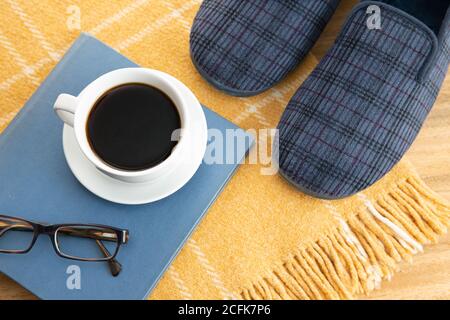 Male home slippers, coffee, book and wool blanket. Home relaxing in wintertime concept Stock Photo