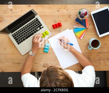 Designer workplace, top view. Home office - desk with laptop, hands with colourful set, color palette selection. Digital tablet and blank white paper for writing Stock Photo