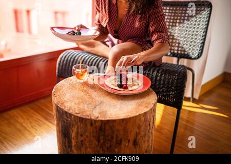 Cropped unrecognizable Woman eating healthy breakfast almond flour pancakes with berries and honey Stock Photo