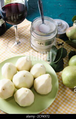 High angle of glass of red wine placed on table with ripe pears on plate prepared for cooking dessert Stock Photo