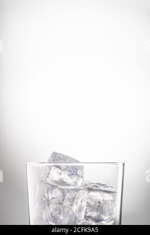 Crystal glass with water and ice cubes placed in studio on white background Stock Photo