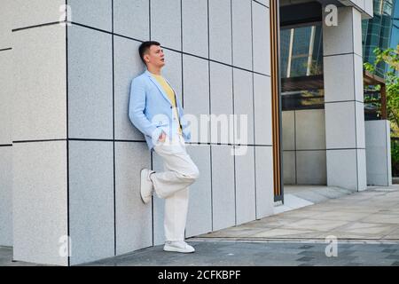 Young man on the street leaning on wall and looking away Stock Photo