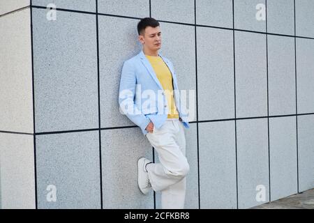 Young man on the street leaning on wall and looking down Stock Photo