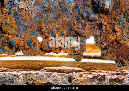 Macro closeup of heavy rust on a metallic door, showing metal damage from rusting away outside. AKA Iron oxide, Iron(III) oxide, Ferric oxide. Stock Photo