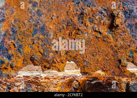 Macro closeup of heavy rust on a metallic door, showing metal damage from rusting away outside. AKA Iron oxide, Iron(III) oxide, Ferric oxide. Stock Photo
