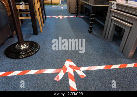 Social distancing floor markings in a small furniture retailer as required under government Covid-19 pandemic safety measures. Stock Photo