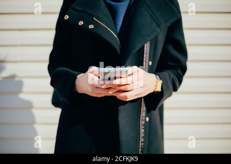Woman dressed in coat walking down the street on spring day Stock Photo