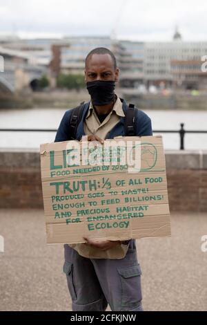 London, UK. 06th Sep, 2020. Extinction Rebellion hold a Flood Alert beach party to highlight the threat of rising tides and the risk of widespread flooding at Oxo Tower Wharf, London, 6th September 2020. A black male protestor holds a placard highlighting wasted food Credit: Denise Laura Baker/Alamy Live News Stock Photo