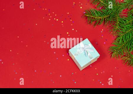 Gift or gift box, spruce branches and confetti stars on the red table top view. Flatley composition for Christmas or New Year Stock Photo