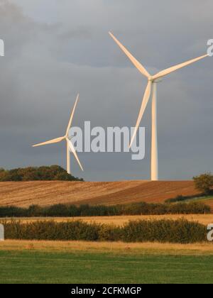 Wind turbines on the horizon at twilight with a dark, brooding sky behind them, a Northamptonshire landscape. Stock Photo