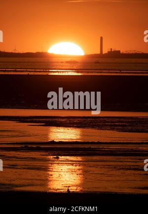 The sun sets behind a power plant on Cape Cod on a summer evening. Stock Photo