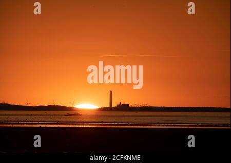 The sun sets behind a power plant on Cape Cod on a summer evening. Stock Photo