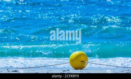 Yellow buoy on a sandy beach on a rope Stock Photo