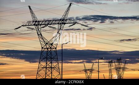 Power transmission towers silhouettes at sunset. Stock Photo