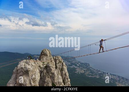 Mishor, Yalta, Crimea, Russia - September 14, 2018: Tourists walk on a rope bridge stretched between the teeth of mount AI-Petri. A popular tourist at Stock Photo