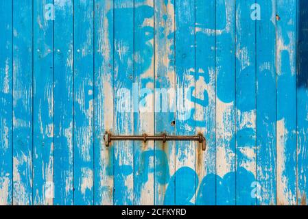 Weathered wooden colorful door with rusty metal bolt on sunny day in Sa Caleta Stock Photo