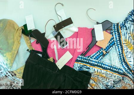 New clothes with tags on hangers for sale. Women's tops, blouses, pants clothing with altered tags so no name identification in view. Stock Photo