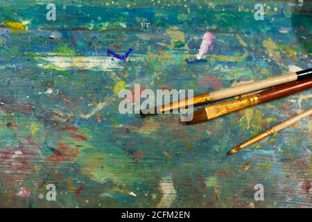 Brushes on an easel stained with paints in the artist's studio. Stock Photo