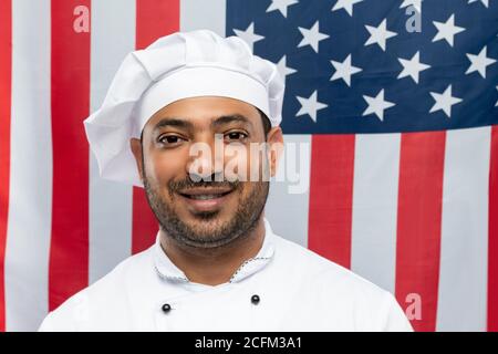 Young smiling chef of restaurant in white uniform standing in front of camera Stock Photo