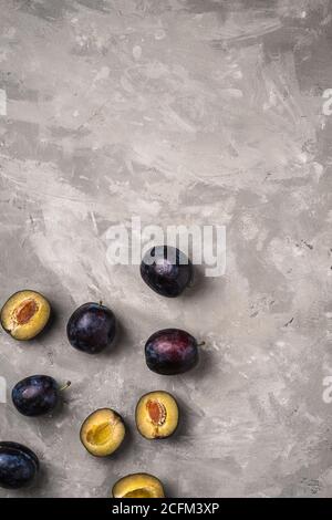 Fresh ripe plum fruits whole and sliced on stone concrete background, top view copy space Stock Photo