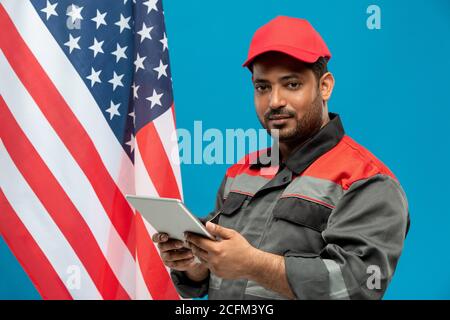 Young serious middle aged factory worker or repairman in workwear using touchpad Stock Photo