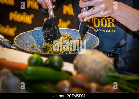 Vegetables and fruit – including limes, chillies and a celeriac – lie in the foreground while the green pistachio mash is worked further in a pan in the background, at the gourmet event at the Zurheide delicatessen market on Berliner Allee in Düsseldorf, Germany. Stock Photo