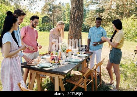 Large group of young intercultural friendly people standing under pine tree Stock Photo
