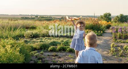childhood, provence style concept - banner 3 year old blonde little girl kid in blue dress and straw hat slavic appearance run along path with toy