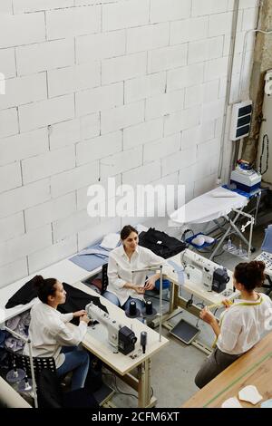 Young confident seamstress consulting her colleagues about some details Stock Photo