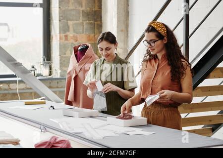 Two young seamstresses packing new shoulder pads for coats, jackets and dresses