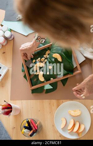 Top view of hand of mature woman making picture composition in wooden frame Stock Photo